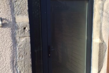 Rénovation avec une porte d'entrée aluminium gris anthracite sablé, accompagnée d'un fixe latéral et d'une imposte cintrée, le tout posé par votre installateur Solabaie la Menuiserie Saint Romanaise