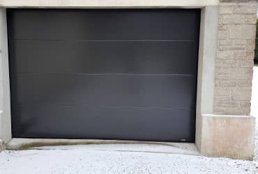 Porte de garage sectionnelle motorisée installée par votre artisan Solabaie Renov' Habitat dans la Manche sur la commune de Terres-et-Marais