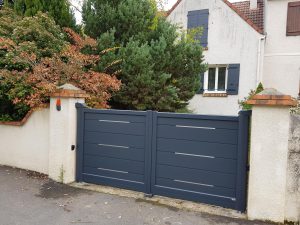 Portail battant aluminium sur mesure modèle Lee, installé par D'Eco Ouest sur cette maison avec motorisation et volets battants assortis