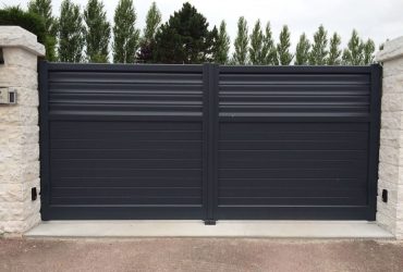 Portail aluminium sur mesure motorisé installé sur la commune de Créances, avec clôture assortie, motorisation pour ouverture battante, interphone et digicode