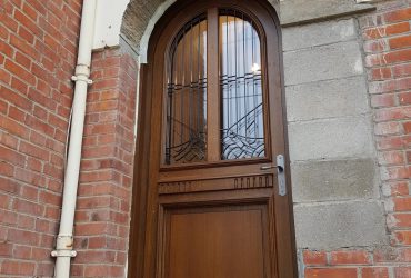 Porte d'entrée bois cintrée avec vitrage et barreaux, installée par D'Eco Ouest, votre installateur Solabaie