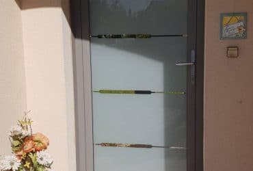 Porte d'entrée aluminium grise Grand vitrage modèle Baguio à vitrage feuilleté, installée par votre professionnel Solabaie ADECI.