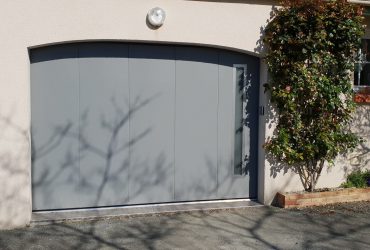 Porte de garage latérale grise modèle Louxor avec hublots aluminium Regard, posée par ADECI, installateur Solabaie